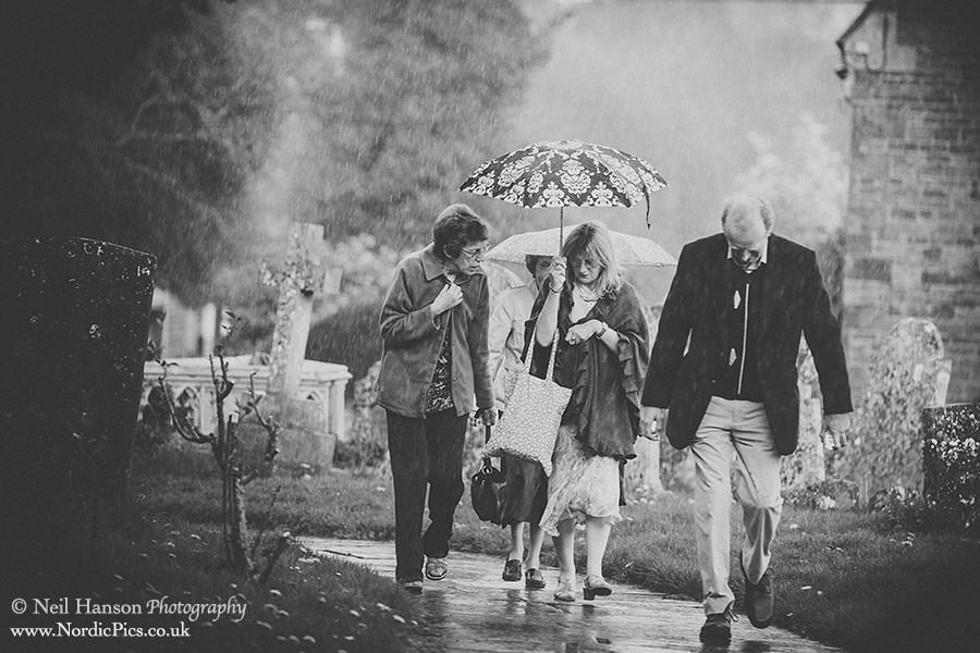 Wedding guests arriving during a thunderstorm at St Marys Church Adderbury