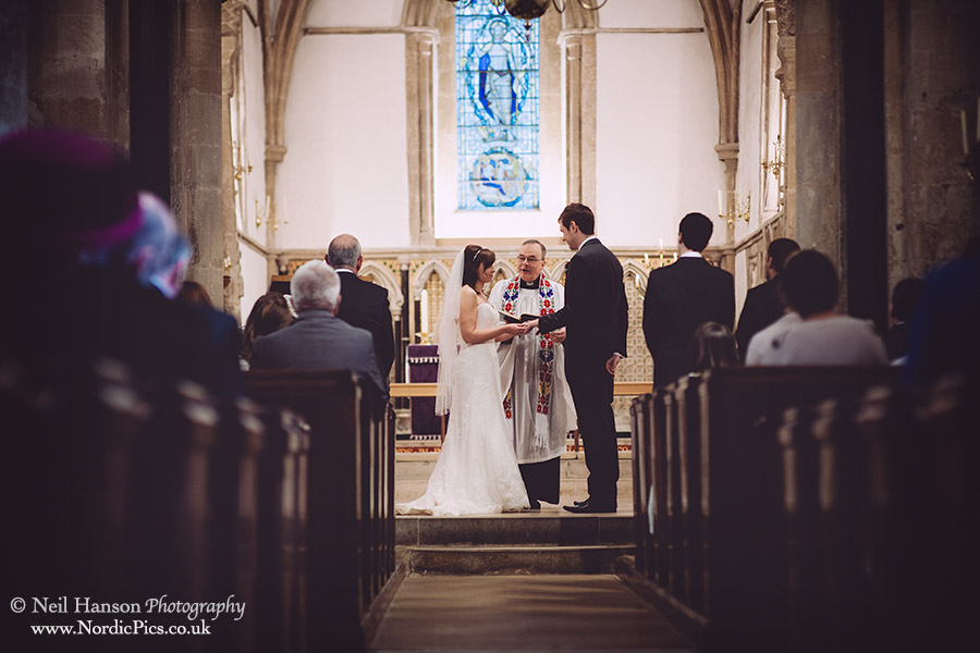 Bride and groom exchange wedding rings at a wedding ceremenoy at St Marys Church Iffley