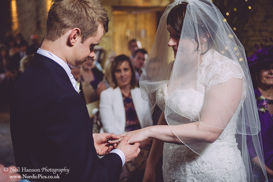Bride & groom exchange rings during the ceremony at Cripps Barn