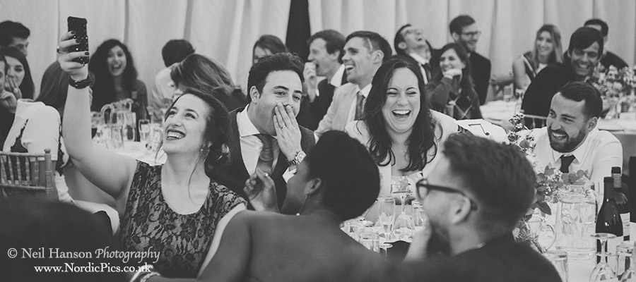 Guests laugh at the speeches on a marquee wedding day