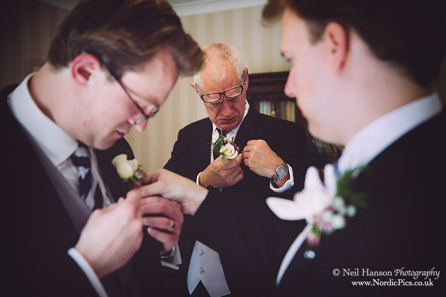 Boys put on their buttonholes at a Wedding at Worton Park in Oxfordshire