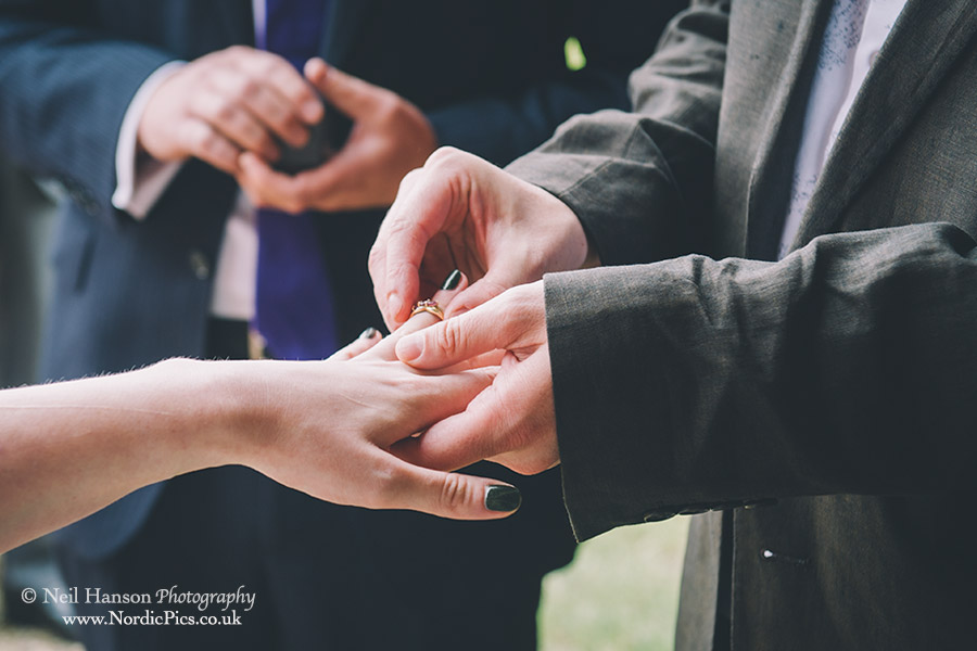 Groom places ring on bride finger at a Cogges Farm Wedding