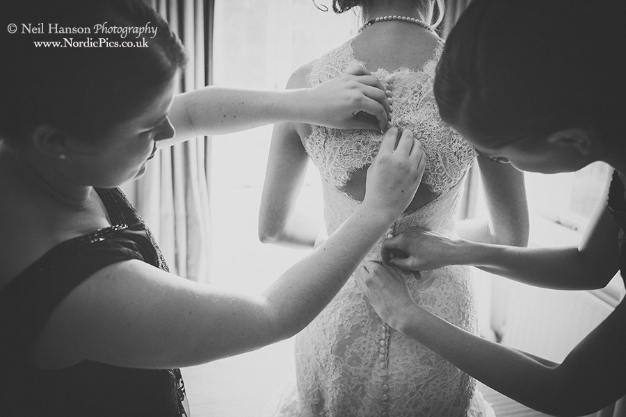 Wedding dress being buttoned up by the bridesmaids