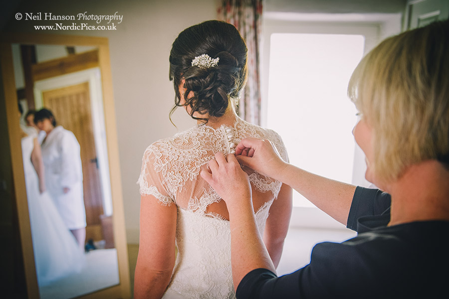 Mother of the Bride doing up the Brides Wedding dress at Caswell House