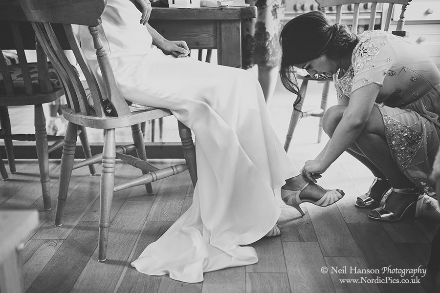 Brides shoes being out on by a bridesmaid