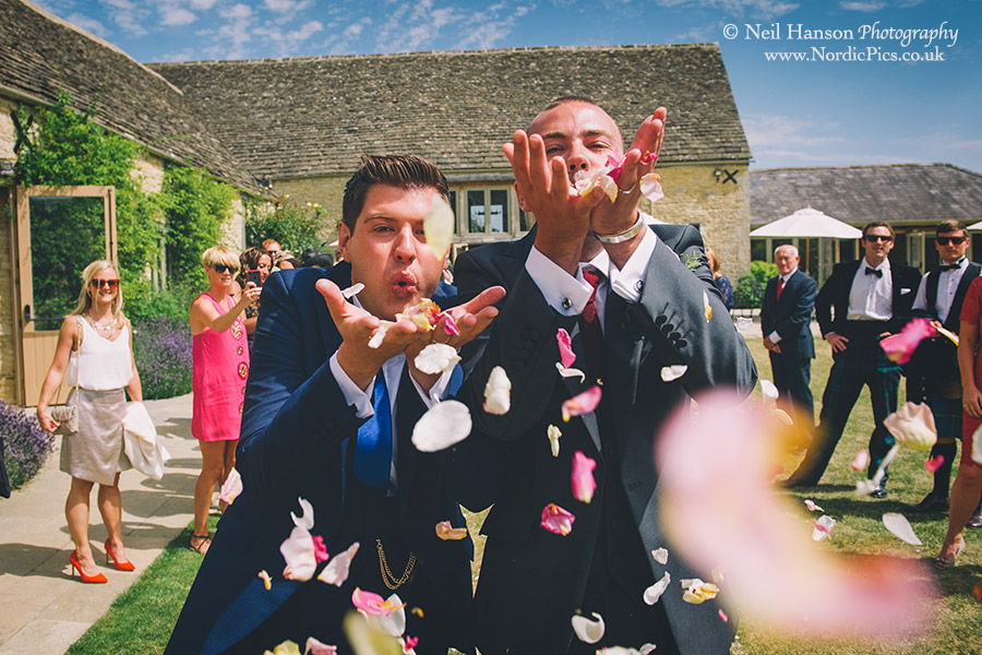 Grooms blowing confetti into the camera on their same sex wedding day