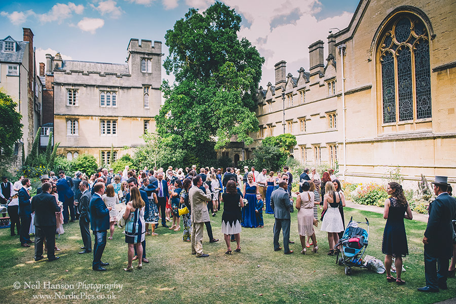 Wedding guests enjoying the drinks reception in the grounds of University College Oxford