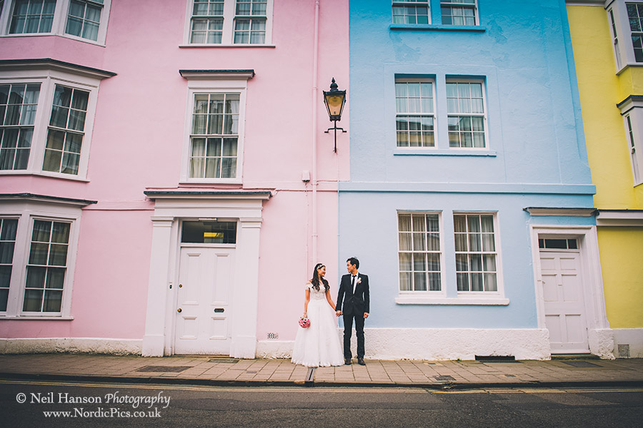 Bride and Groom holding hands outside some colourful houses in Oxford