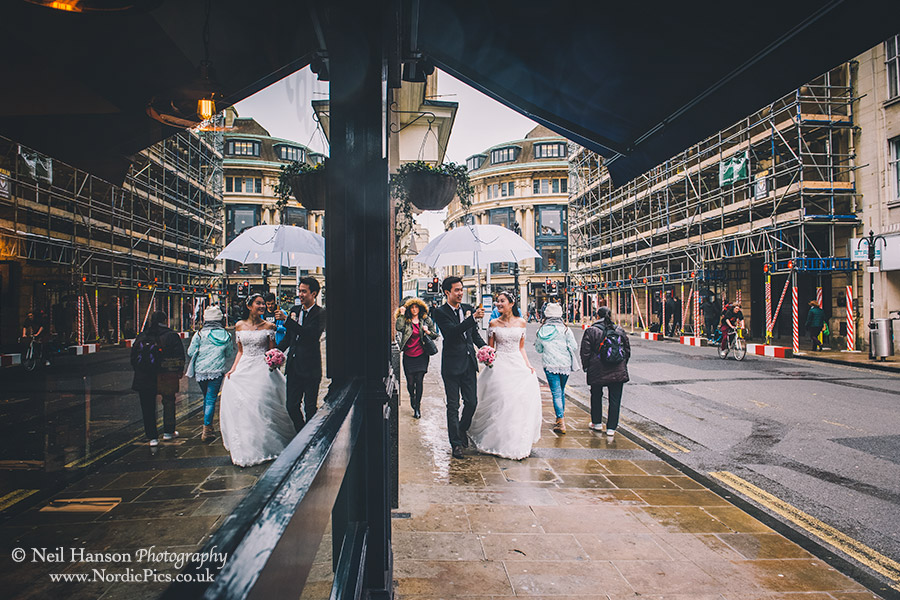 Bride and Groom holding umbrellas in the rain in Oxford