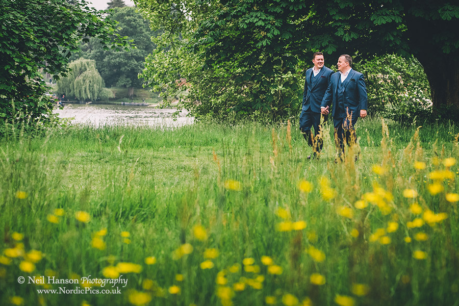 Both grooms walking around the lake at Hever Castle on their Wedding Day