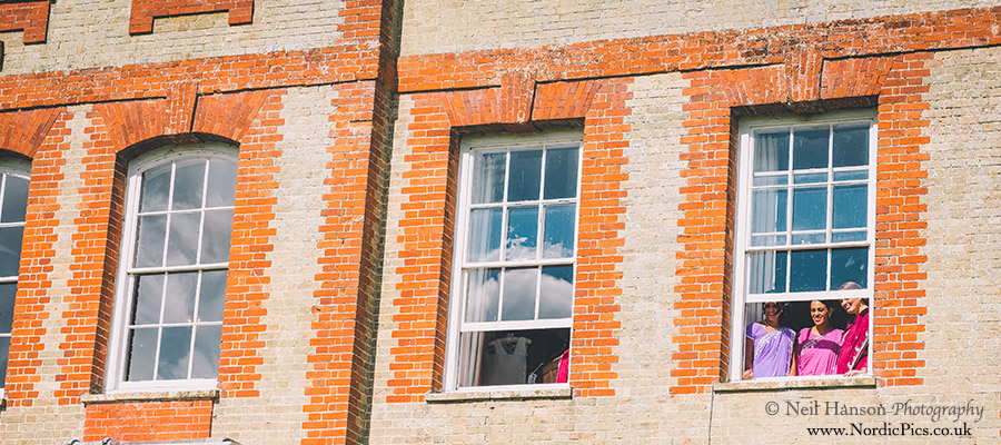 Bridesmaids watch from their bedroom window
