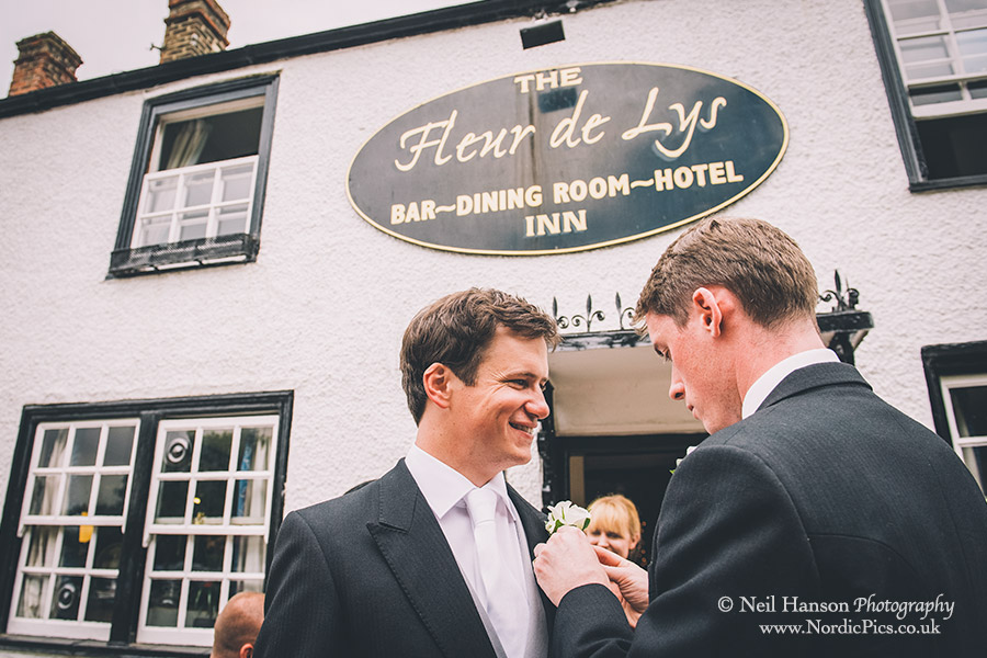 Groom having his buttonhole put on by the best man