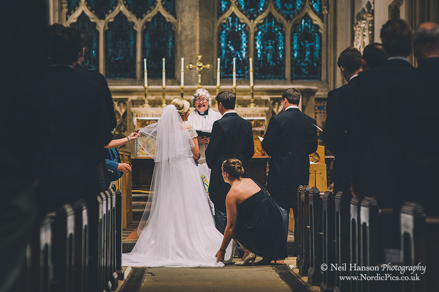 Bridesmaid tends to Brides dress at a Dorchester Abbey Wedding
